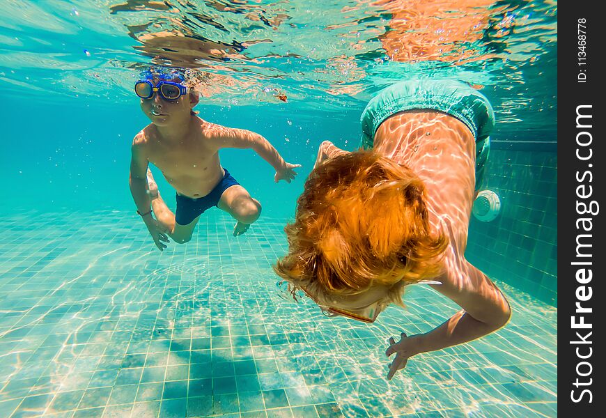 Two children diving in masks underwater in pool