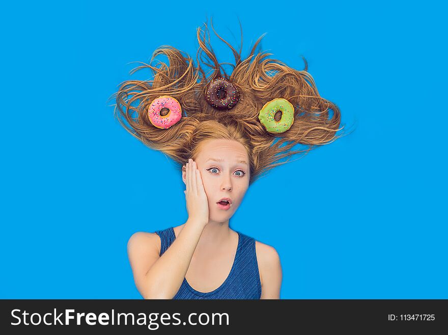 Young woman with donuts in her hair. Multicolored donuts. Harm of sweet.