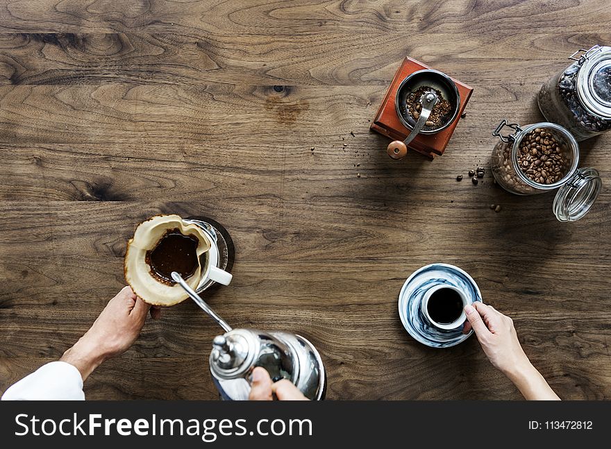 Person Making Coffee Beside Person Holding Cup of Coffee