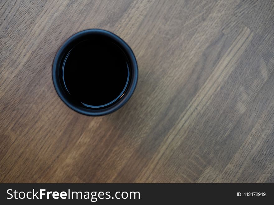 Black Plastic Cup In Top Of Brown Wooden Surface