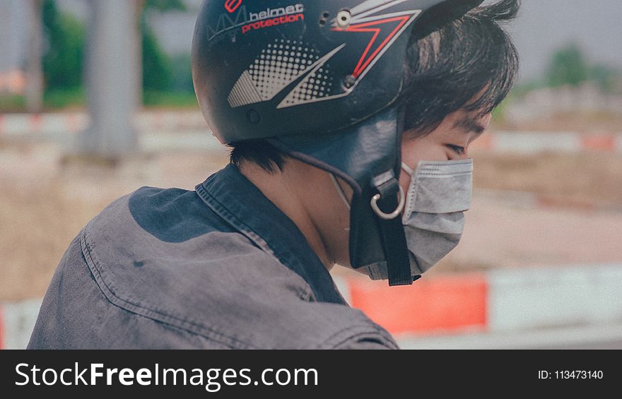 Selective Focus Photography of Person Wearing Black and Red Helmet and Gray Mask