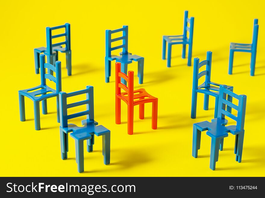 Unique red chair in a group blue others. Leadership concept. Empty chairs on yellow background. The concept of uniqueness, distinction from others.