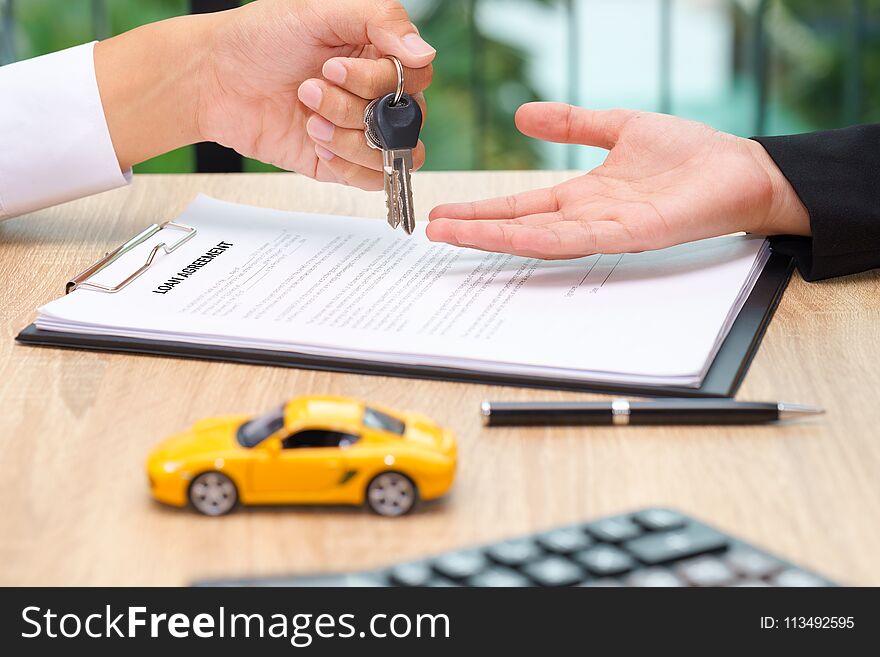 Businessman giving car key over loan agreement document with car