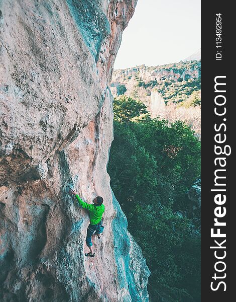 A man climbs the rock. Climbing in nature. Fitness outdoors. Active lifestyle. Extreme sports. The athlete trains on a natural relief.