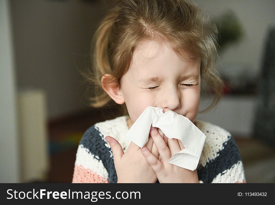 Sick little girl covering her nose with handkerchief