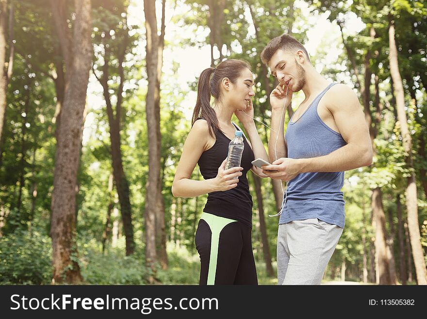 Young couple listening music and relaxing, preparing for jogging, copy space. Young couple listening music and relaxing, preparing for jogging, copy space