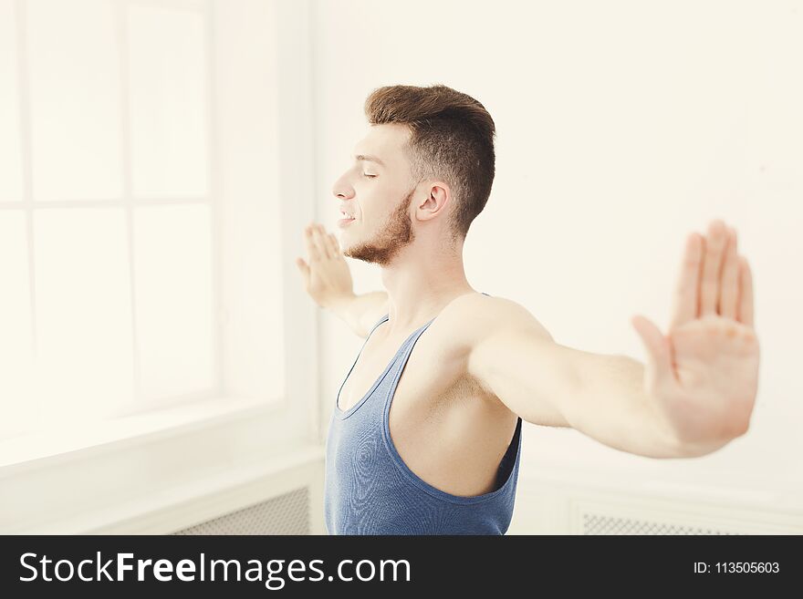 Man training yoga pose in gym at white background, copy space. Young boy makes exercise, fitness, meditation. Man training yoga pose in gym at white background, copy space. Young boy makes exercise, fitness, meditation