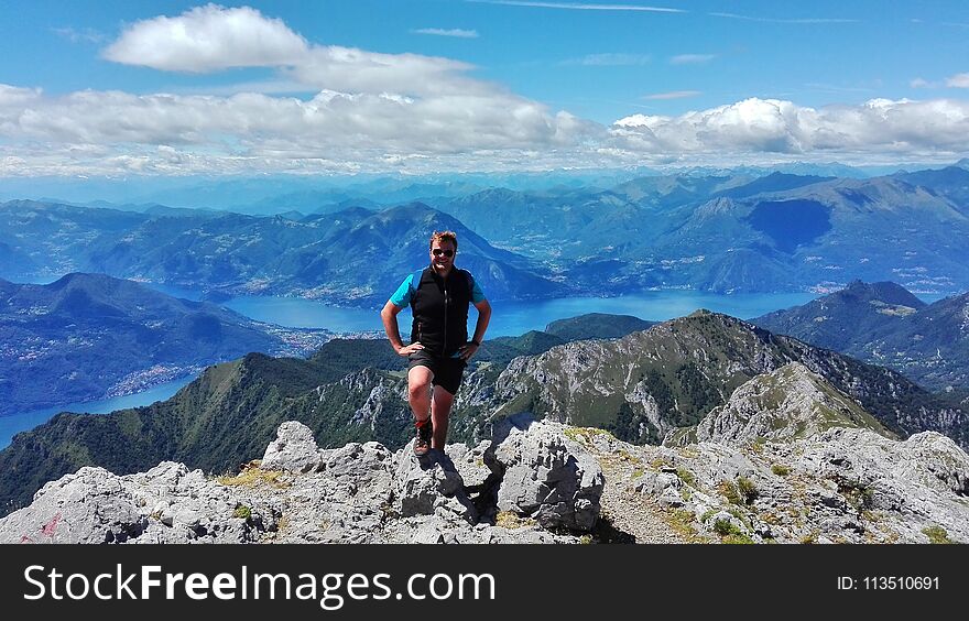 An hiker smiling in fronto of the panorama of the lake of Como and lecco and resegone