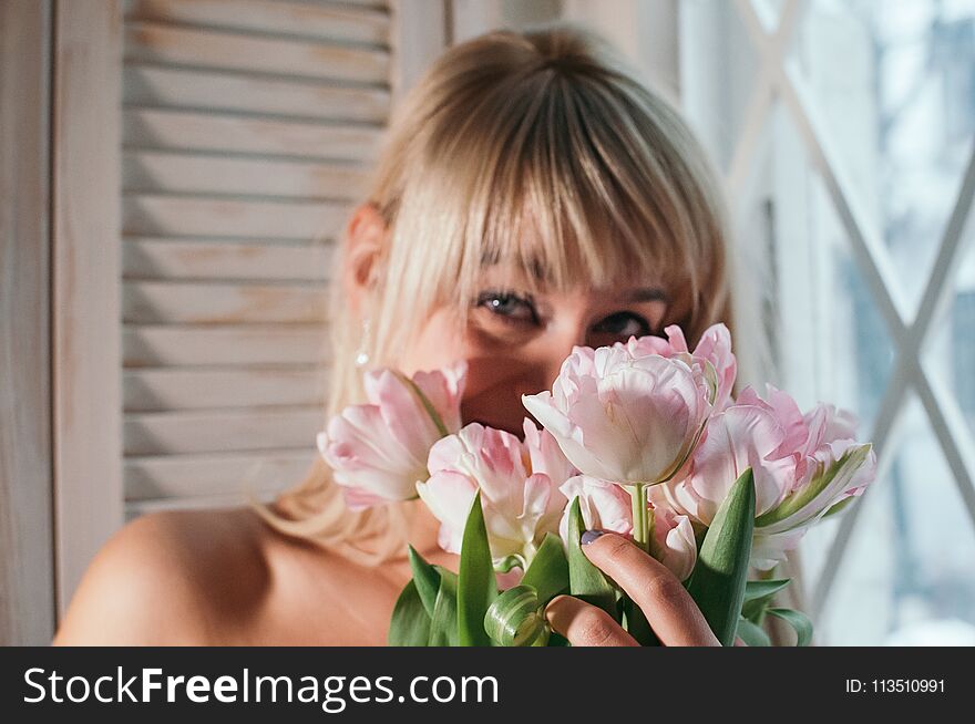 A blurred view of a woman holding flowers by the window, smiling