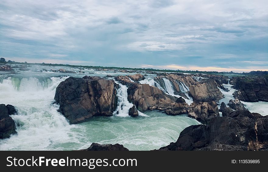 Landscape Photography Of Rocks On Body Of Water