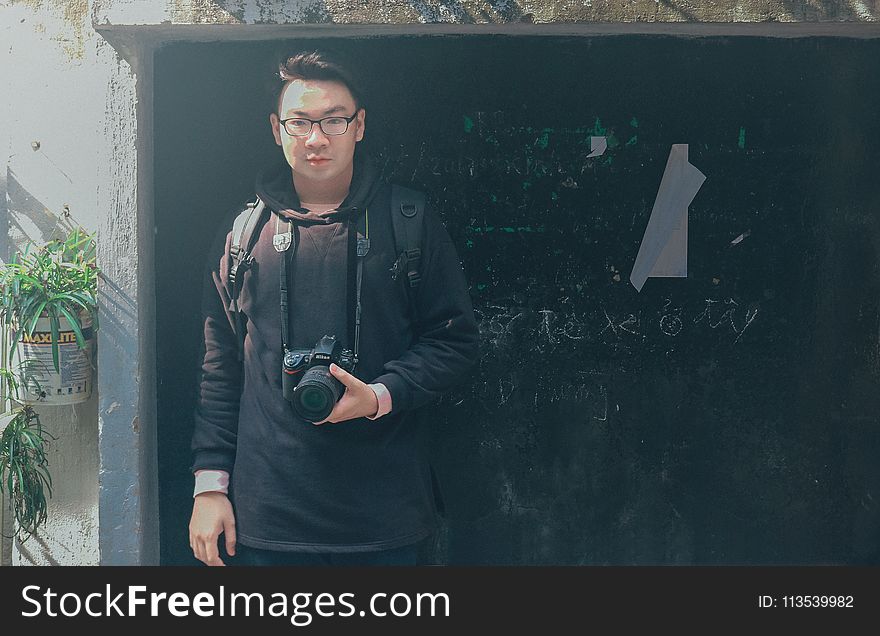 Man in Black Pullover Hoodie Holding Black Dslr Camera