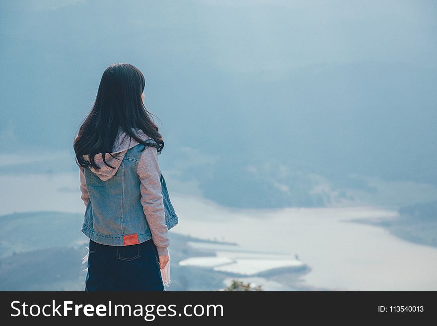Woman in Gray and Blue Zip-up Hoodie Standing on the Cliff