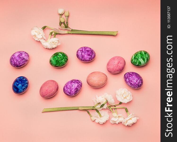Festive composition, colorful Easter eggs and daffodils on a pink background