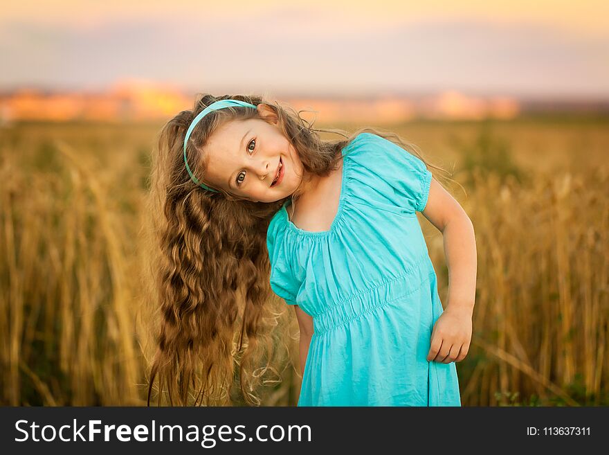 Happy girl in wheat field on warm and sunny summer evening