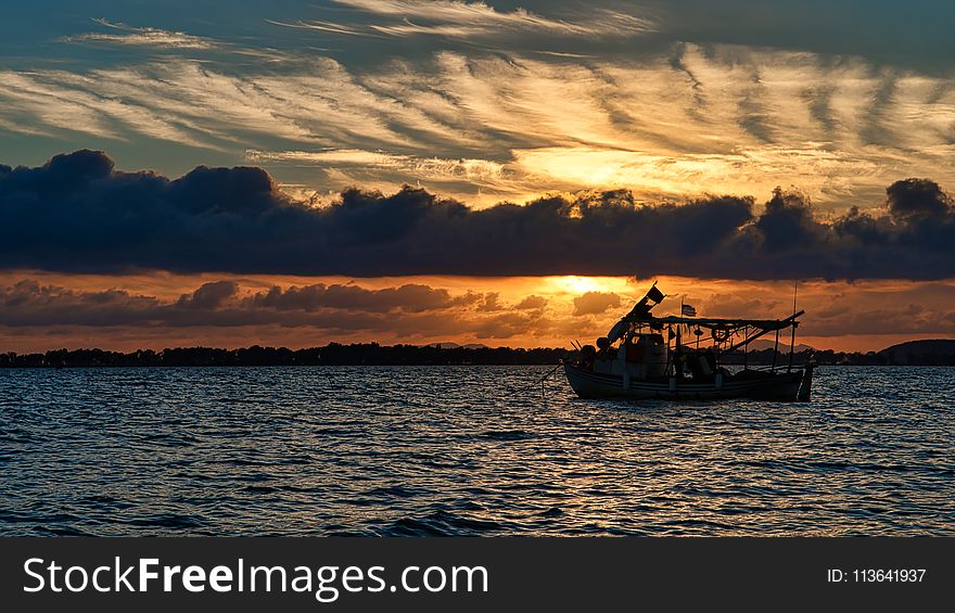 Silhouette Photo of Boat on Ocean during Golden Hour