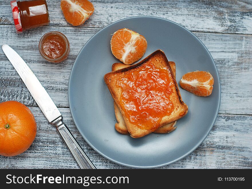 Fresh Toasts with Homemade Orange Jam on Gray Plate over Wooden Background.