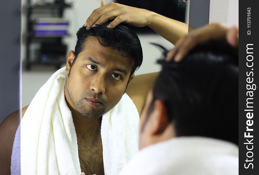 Indian asian man looking after his appearance in front of a mirror beauty styling lifestyle.hair styling