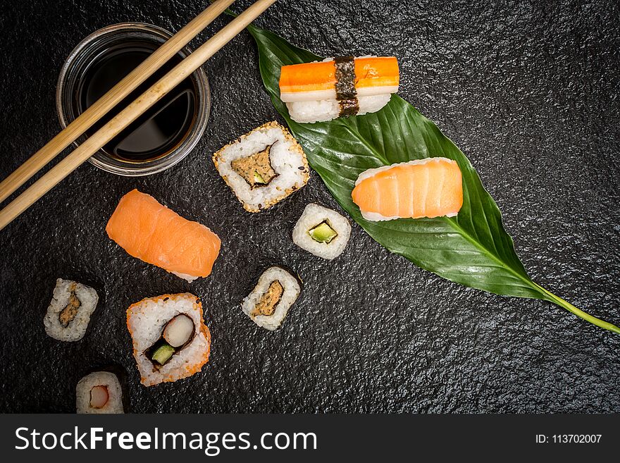 Traditional japanese sushi rolls hosomaki,uramaki, nigiri and chopsticks and soy sauce on stone desk top view. Traditional japanese sushi rolls hosomaki,uramaki, nigiri and chopsticks and soy sauce on stone desk top view