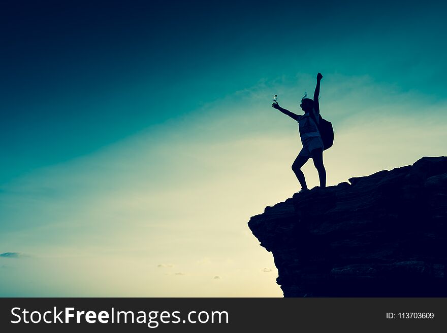 Silhouette sporty woman on the cliff. Sunset and high mountain. Business Success and goal. Silhouette sporty woman on the cliff. Sunset and high mountain. Business Success and goal.