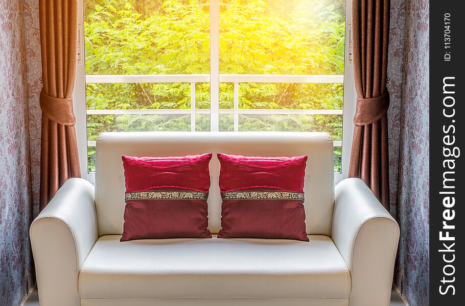 Double red cushions on white sofa in living room inside windows. Double red cushions on white sofa in living room inside windows
