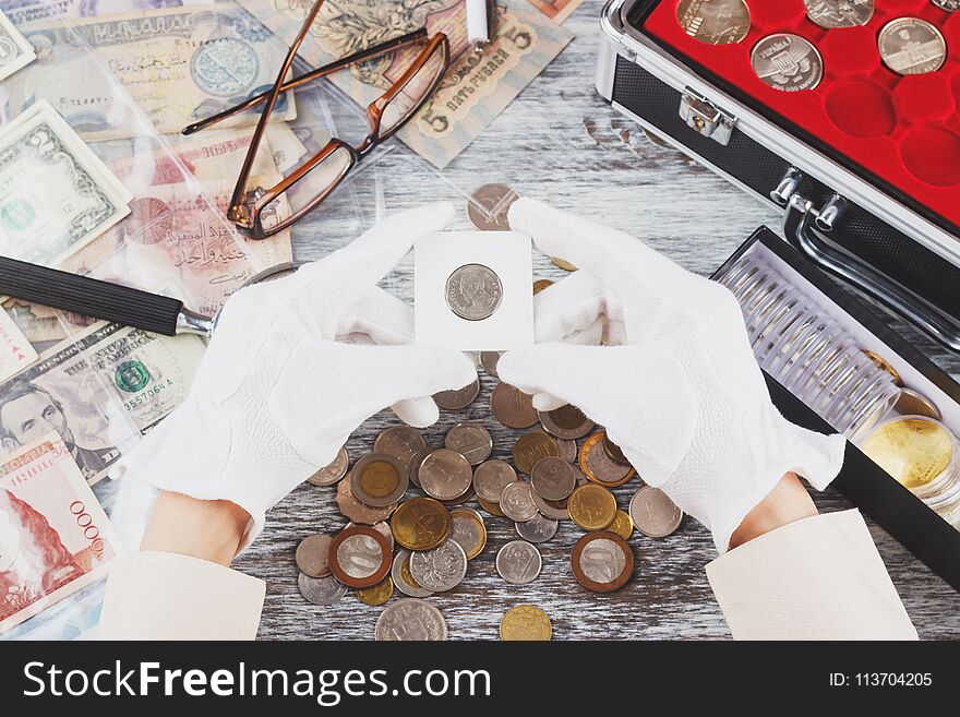 Hands in the gloves hold flip with collector coin, soft focus background