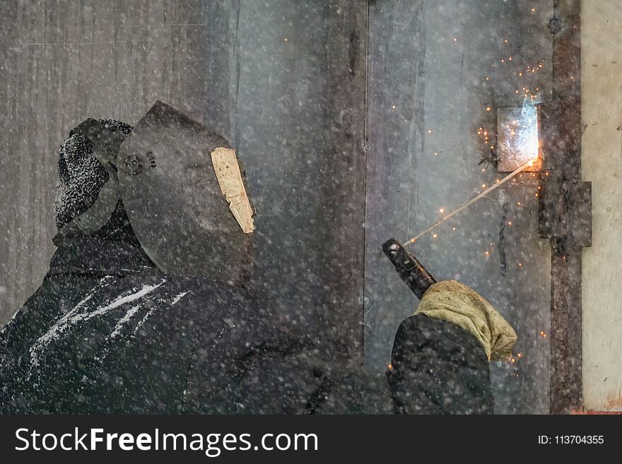 Welding a man repairs a garage outdoors. Welding a man repairs a garage outdoors