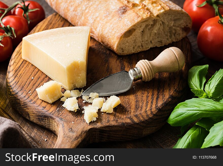 Parmesan cheese and fresh ciabatta bread on wooden cutting board, closeup view, selective focus