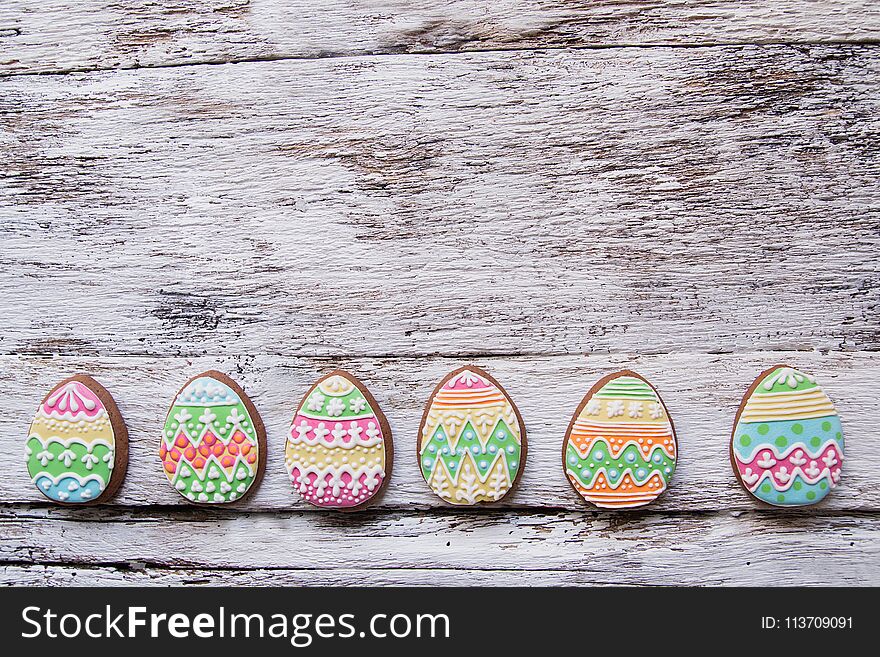 Gingerbread cookie in the form of color eggs on dark wooden background. Happy Easter card. Bright biscuits. Treats for children. copy space