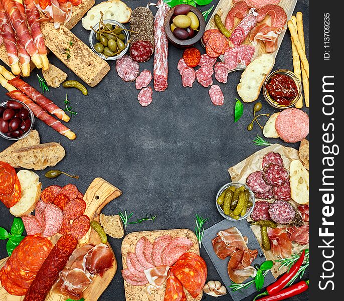 Italian meat appetizer snack set. Variety salami, prosciutto, bread sticks, olives, capers on concrete background. Italian meat appetizer snack set. Variety salami, prosciutto, bread sticks, olives, capers on concrete background