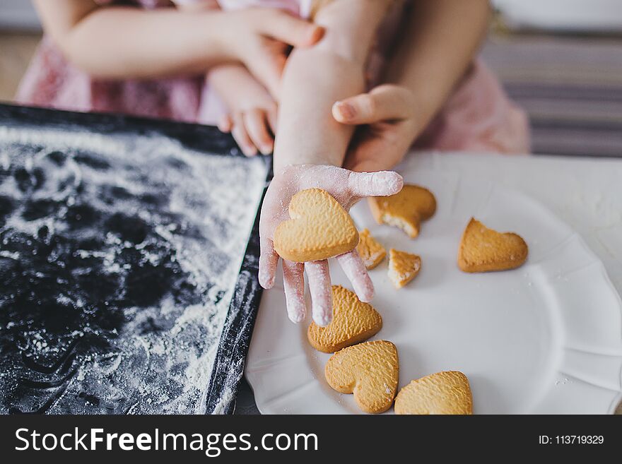 Mom and daughter lay out cookies on a white plate. Mom and daughter lay out cookies on a white plate