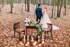 Beautiful Wedding Couple Holding Hands Near The Vintage Table In Autumn Forest Royalty Free Stock Photography