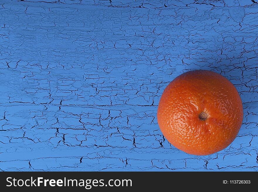 Orange mandarin on a blue background with craquelures.