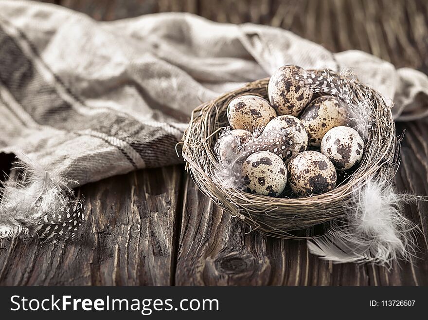 Quail eggs in a nest on a rustic wooden background.