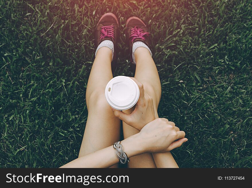 Sport young asian woman sitting on grass, drinking coffee. Resting Runner. Vintage filter.