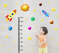 Closeup Happy Asian Kid Stand And Point To Scale Of Measure Height With Cute Cartoon At The Marble Stone Wall Textured Background Stock Images