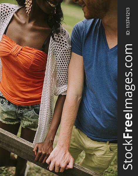 Hands of young multiracial couple on the wooden fence in the park. Hands of young multiracial couple on the wooden fence in the park