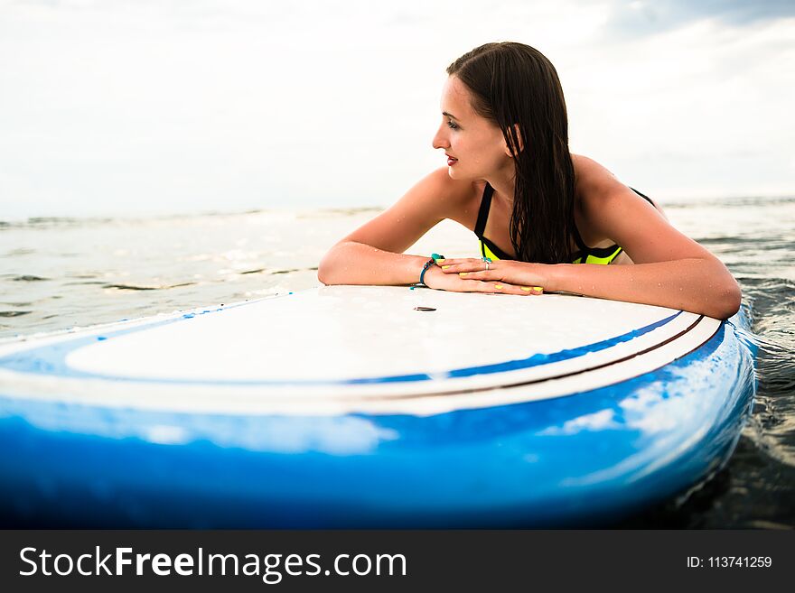Woman surfer paddling prone on surfboard to the open sea for surfing. Woman surfer paddling prone on surfboard to the open sea for surfing