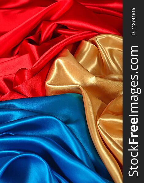 Natural golden, blue and red satin fabric as background texture. Natural golden, blue and red satin fabric as background texture