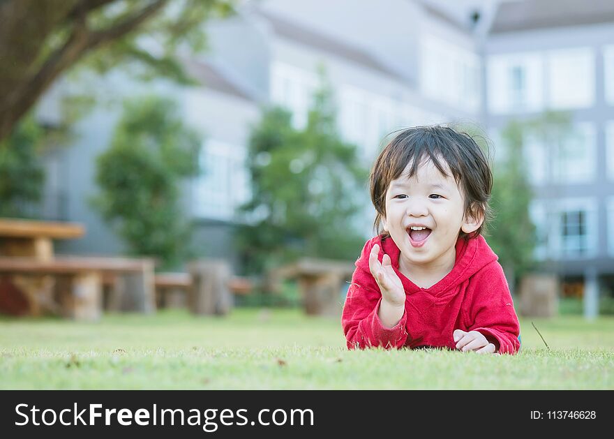 Closeup happy asian kid lied on grass floor in the garden background with cute motion