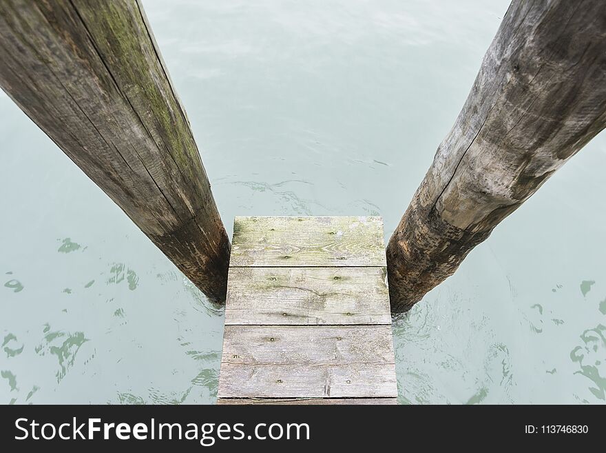 Wooden pier between two pillars on water in Venice, Italy. Wooden pier between two pillars on water in Venice, Italy