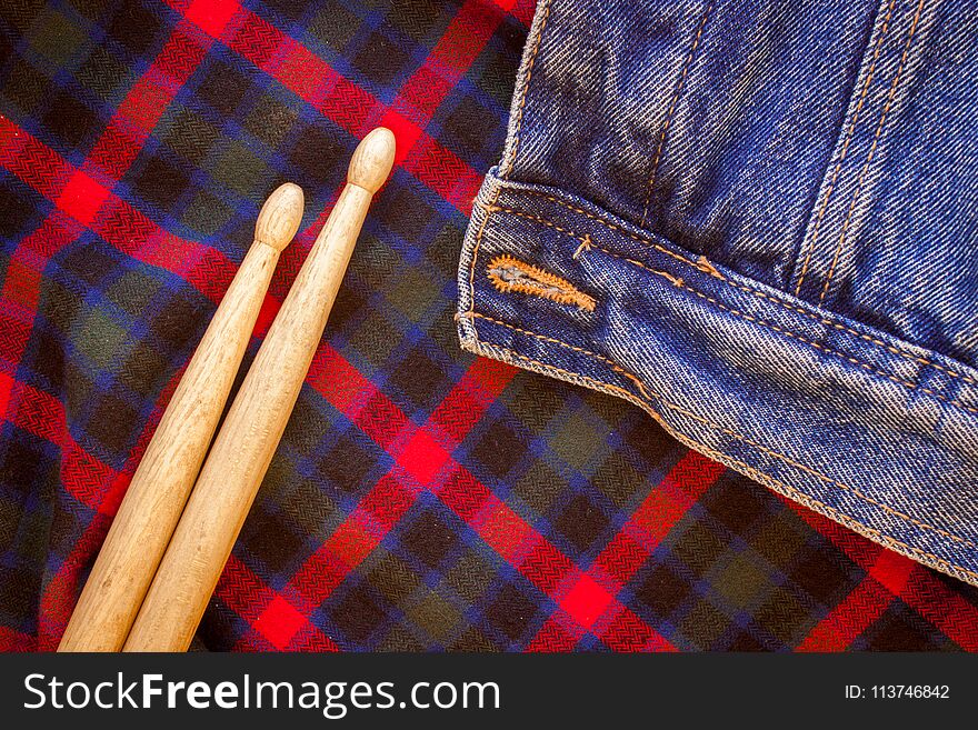 Two drum sticks of oak lie on the fabric of a Scottish cage and jeans. Two drum sticks of oak lie on the fabric of a Scottish cage and jeans