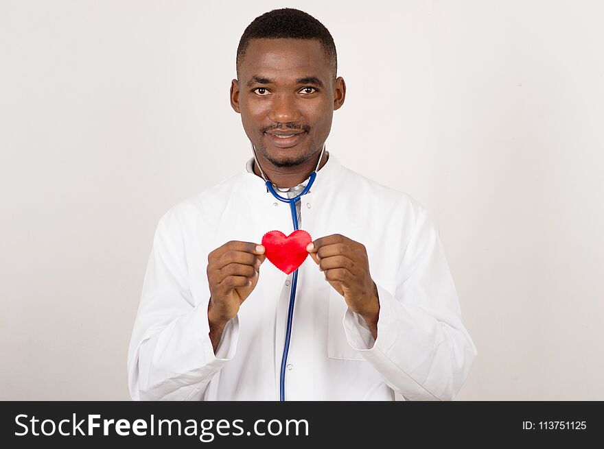 Young smiling doctor man holding and presenting a red heart in his hand