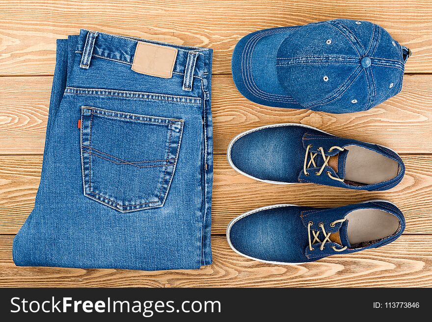 Jeans, Shoes And A Cap On A Wooden Background