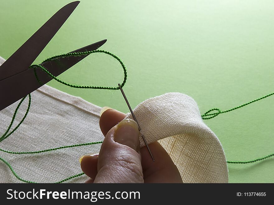 Closeup of hands with thread and needle sewing tools. Closeup of hands with thread and needle sewing tools