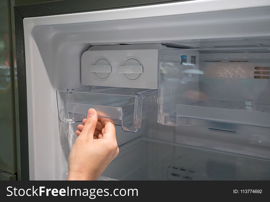 Woman hand open clear plastic ice container drawer in new refrigerator. Woman hand open clear plastic ice container drawer in new refrigerator.