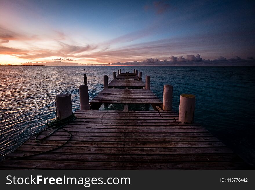 Wooden pier on the sea during sunset. Beautiful orange purple sk