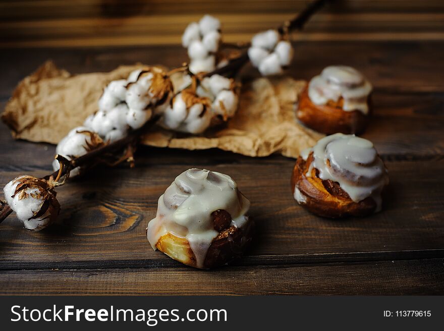 Small buns with custard and cotton flowers decoration on wooden area. Small buns with custard and cotton flowers decoration on wooden area