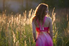 Attractive Young Woman Walking On Meadow At Sunset - Rear View Royalty Free Stock Photo