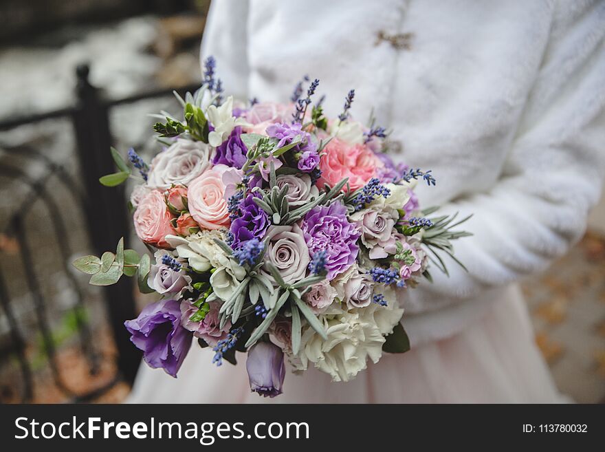 Bride holds wedding bouquet from colorful roses