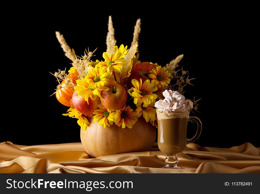 The original bouquet in the pumpkin and Cup of cappuccino on silk fabric, isolated on black